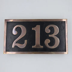 Brass house number plate with '213' on a black background with bronze border