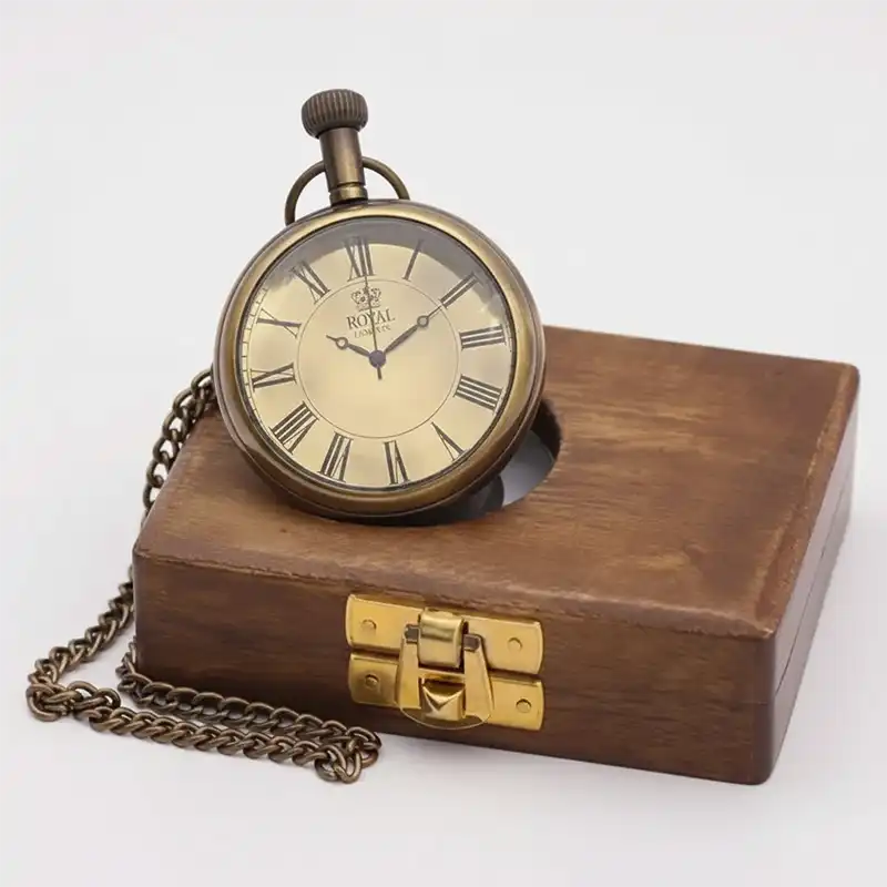 Vintage-style pocket watch with chain on a wooden box against a white background