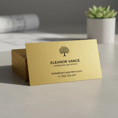 Gold business card with a logo and text on a table with a blurred background